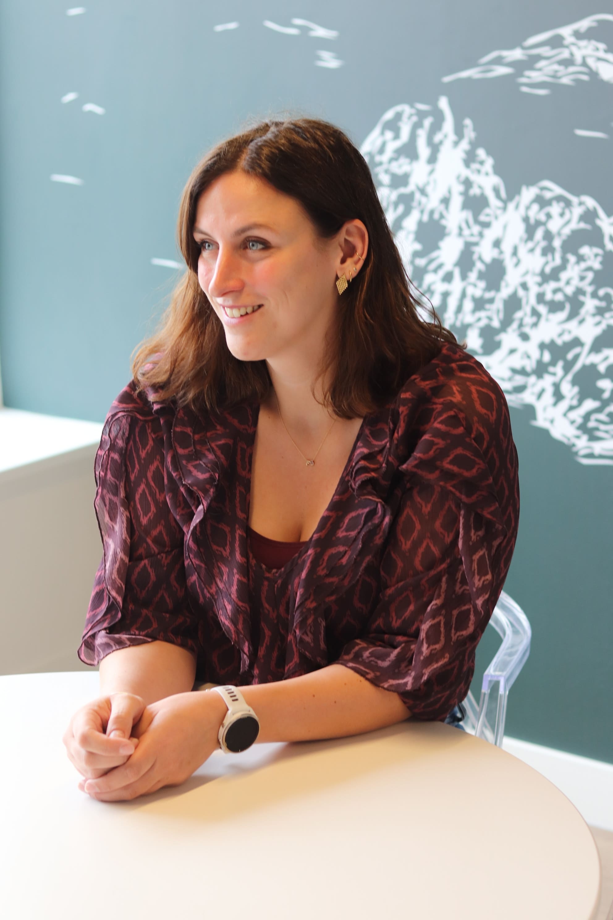 Portret van Novi-expert Zoé Gerritsen, glimlachend aan een witte tafel in een kantooromgeving.