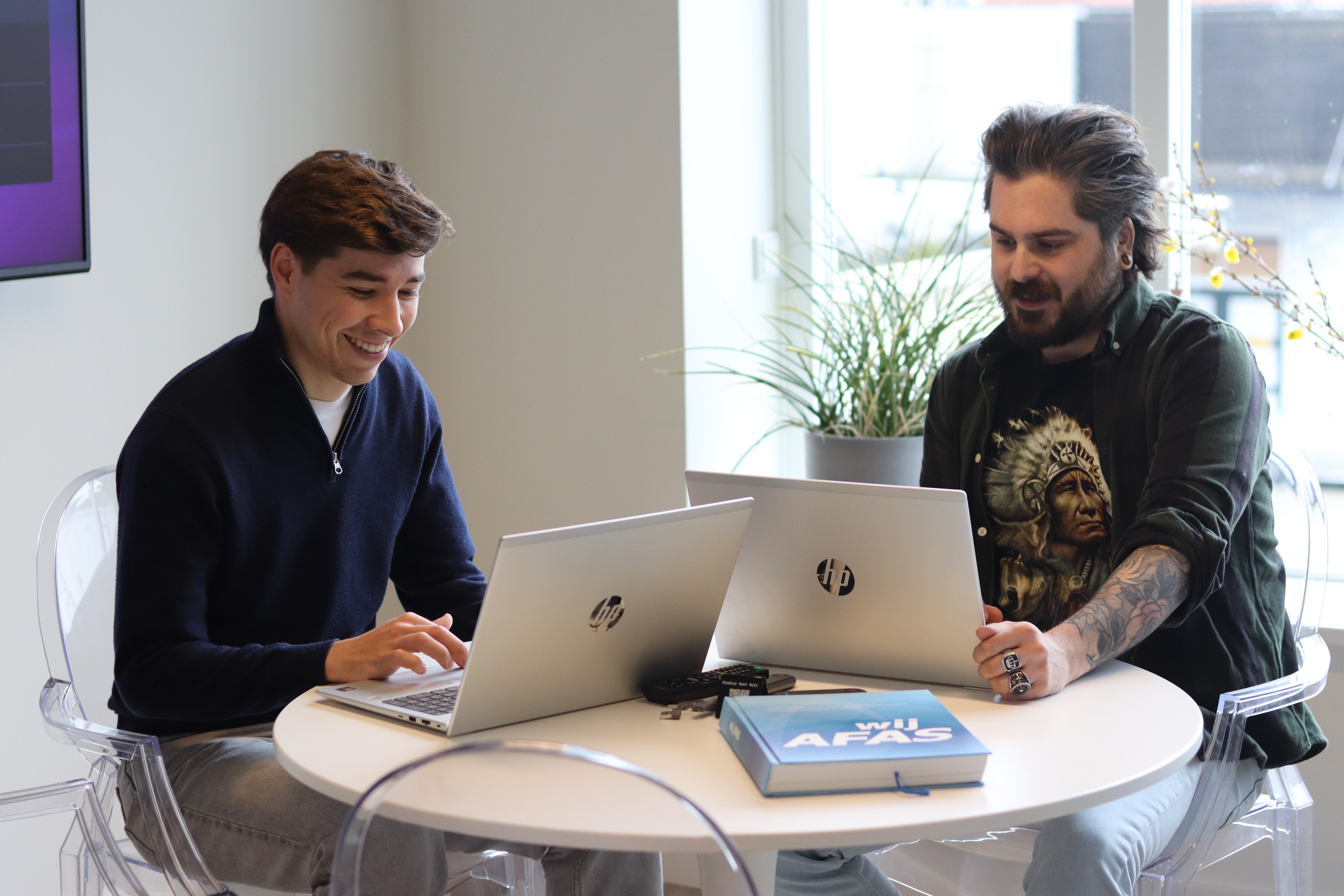 Twee collega’s werken samen aan laptops tijdens een AFAS-werksessie op kantoor.