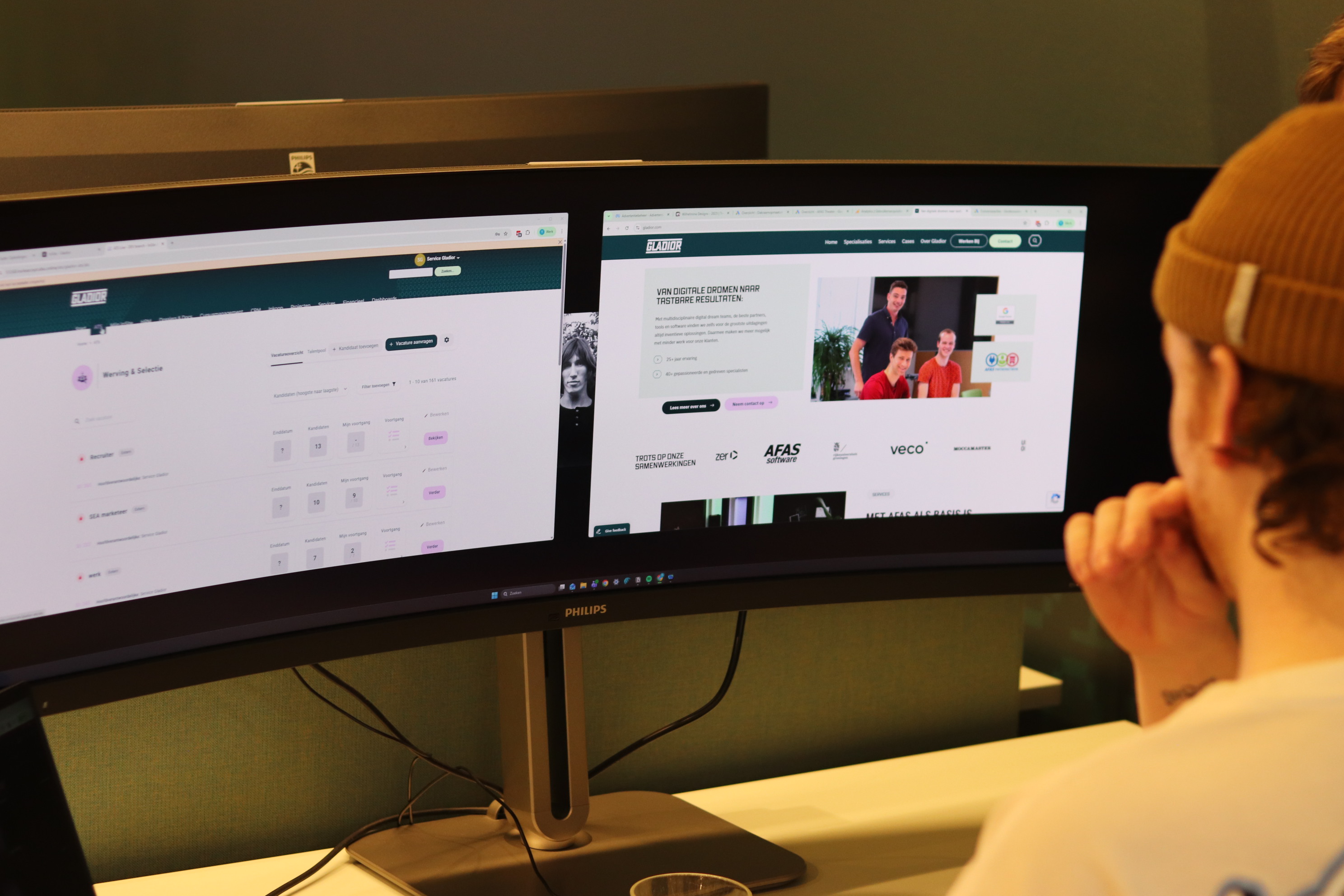 Medewerker bekijkt een recruitmentdashboard en de Gladior-website op een breed beeldscherm.