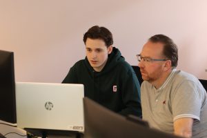 Twee collega’s bekijken samen een laptop tijdens een werksessie op kantoor.