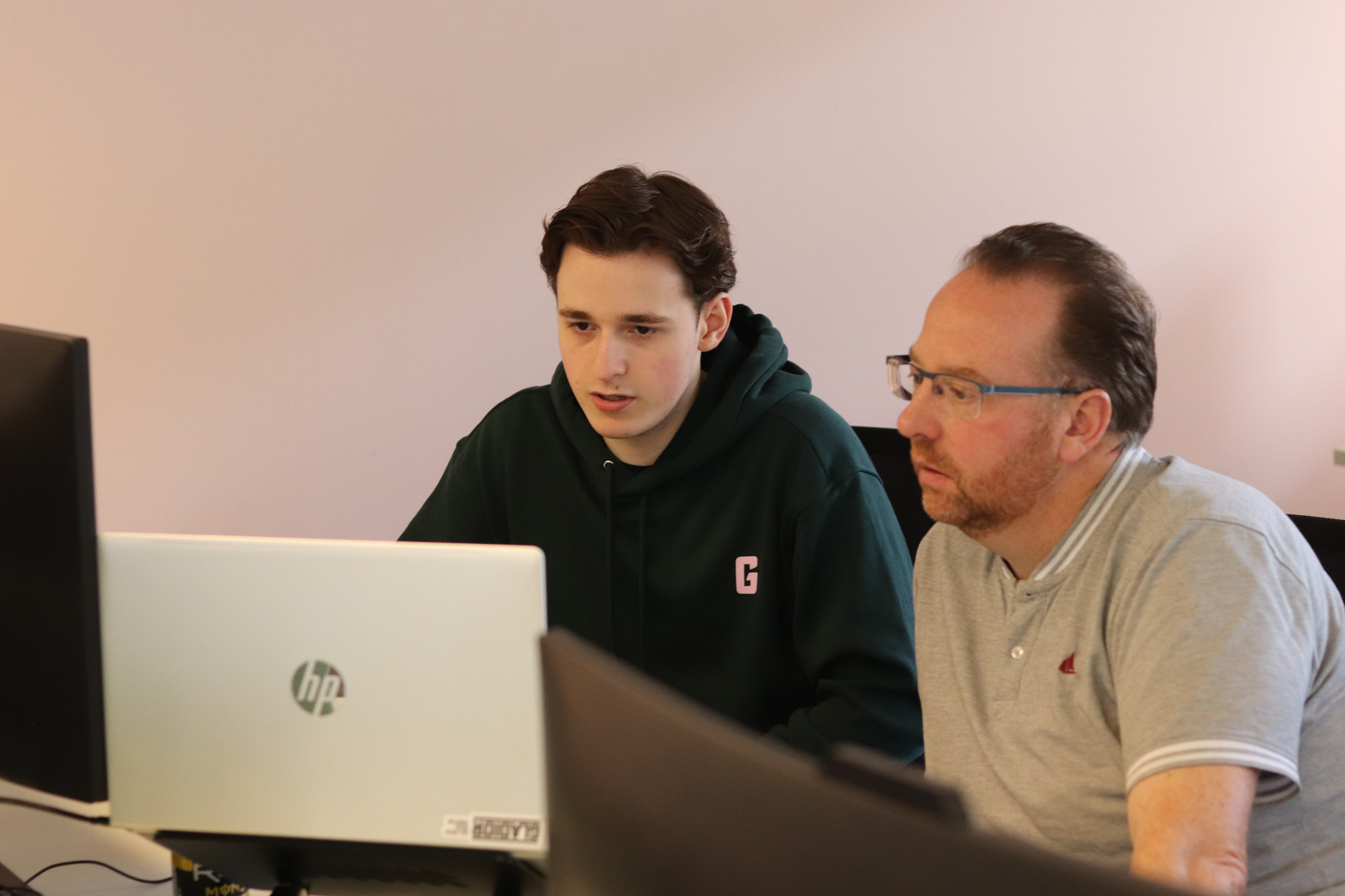 Twee collega’s bekijken samen een laptop tijdens een werksessie op kantoor.