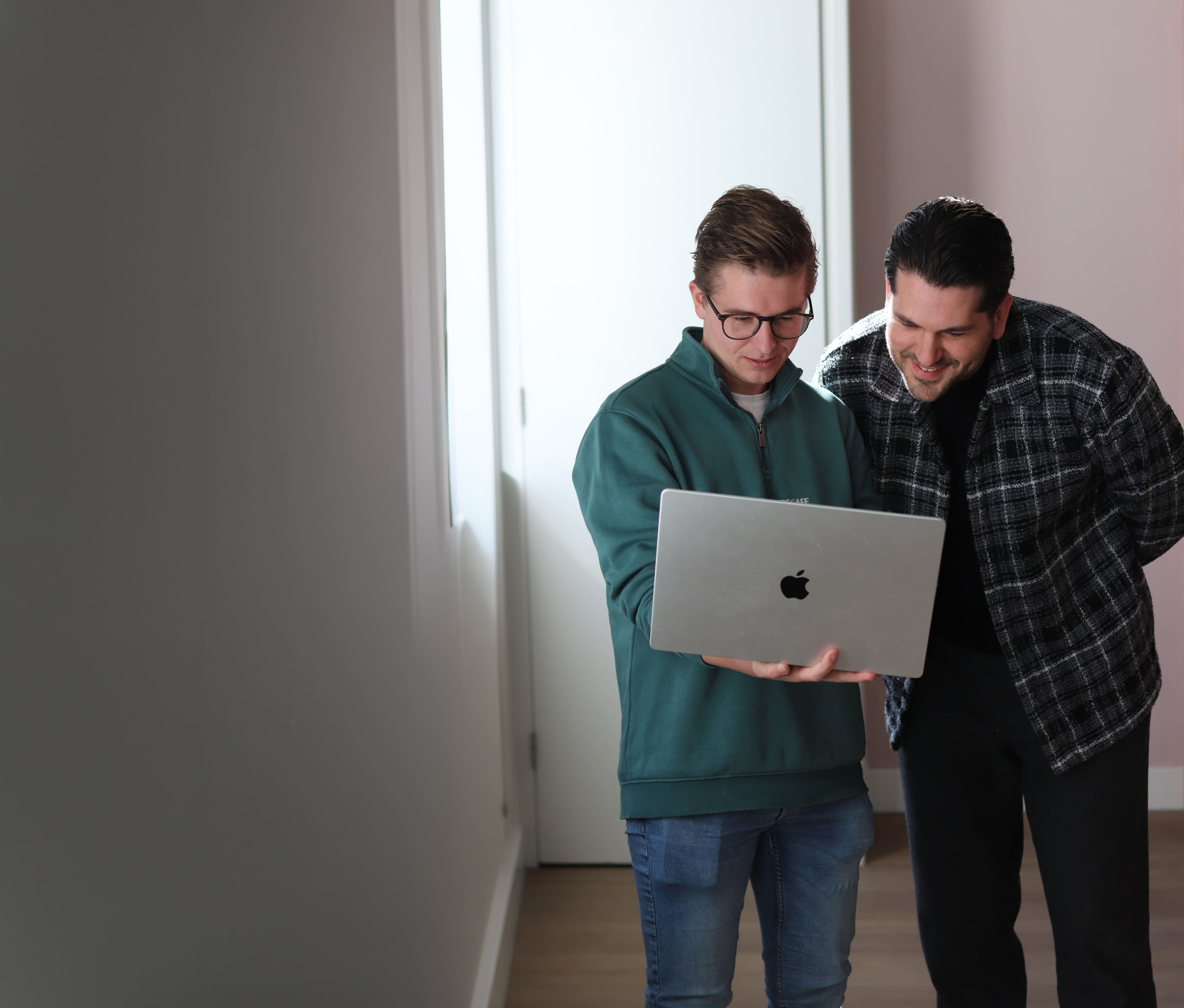 Twee collega’s bekijken samen een laptop tijdens een informeel overleg op kantoor.
